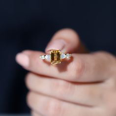 a woman's hand holding an engagement ring with a yellow and white diamond in it