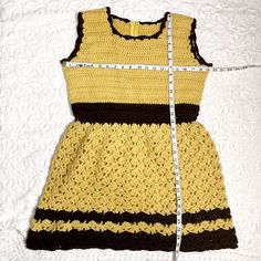 Beyond adorable fit and flare handmade crocheted mini dress in gold and brown. Sleeveless fitted top with back zipper. Open crochet skirt that's semi-full. Zipper is nylon. Worsted weight yarn. Note: it's pinned to fit the dress form. Material / acrylic yarn Care / machine wash For accurate fit, please compare measurements to a similar garment that fits you well. Make allowance for clothes underneath and to allow garment to drape properly. Size on tag / no tags, fits like a mediumish Measurement Fitted Sleeveless Crochet Mini Dress, Fitted Sleeveless Crochet Lace Dress, Fitted Sleeveless Mini Dress With Crochet, Fitted Crochet Lace Dress In Mini Length, Fitted Brown Crochet Top For Spring, Fitted Crochet Lace Top, Fitted Crochet Lace Top Mini Length, Fitted Yellow Crochet Lace Top, Yellow Sleeveless Crochet Lace Top