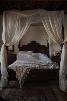 a canopy bed with white drapes over it's head and pillows on the floor