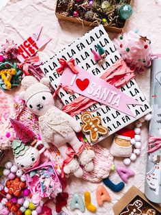 a pile of assorted items on top of a white cloth covered in pink letters