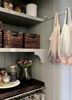 two baskets are hanging on the wall next to some jars and vases with tulips in them