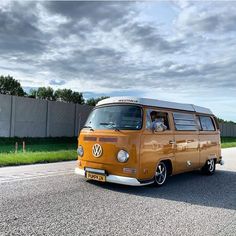 an old vw bus is parked on the side of the road in front of a fence