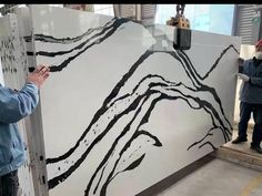 two men working on a large white and black painting