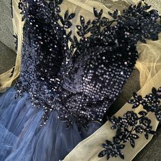 a blue dress with sequins on it sitting on the floor next to a piece of cloth