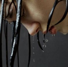 a woman with her eyes closed and water dripping from her nose, looking down at the ground