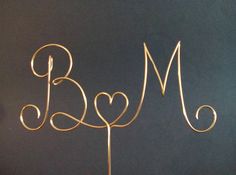 a cake topper with the letter b and heart on it is shown in gold