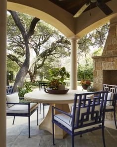 an outdoor dining area with chairs, table and potted plant in the center surrounded by trees