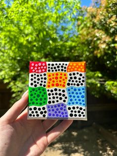 a hand holding up a small square with dots on it