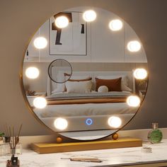 a round mirror sitting on top of a table next to a desk with a laptop