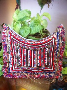 a red, white and blue purse sitting on top of a table next to a potted plant