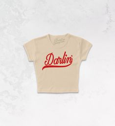 Get all of the southwestern vibes in this Darlin' western inspired retro 90's style baby tee! - Features the phrase " Darlin' " in a red ink - Screen print transfer that is heat pressed onto each tshirt - Tshirt is a super soft, 90s style micro ribbed baby tee - Regular Baby Tee Fit - Cotton / Poly Blend *due to screens and filters colors may vary slightly to photos* Ring-spun Cotton Graphic Tee With Graphic Design, Graphic Tee With Screen Print On Ring-spun Cotton, Graphic Tee With Short Sleeves In Ring-spun Cotton, Ring-spun Cotton Graphic Tee, Retro Washed Black Screen Print T-shirt, 90s Sports, Maxi Dress Pattern, Sporty And Rich, Western Chic