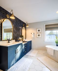 a large bathroom with blue cabinets and white tile flooring, along with an oval mirror on the wall