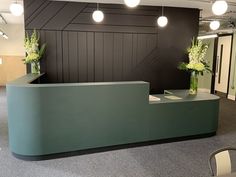 an office reception area with green counter and white flowers in vases on the desk