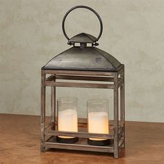 two candles are lit in a metal lantern