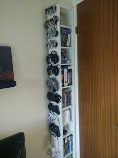 a book shelf filled with video game controllers and gaming accessories next to a door in a living room