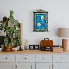 a white dresser topped with lots of drawers and a painting on the wall above it