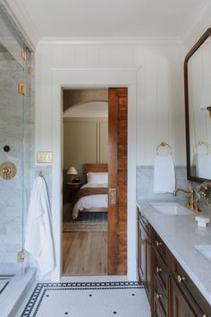 a bathroom with marble counter tops and white walls, along with wooden cabinetry on both sides