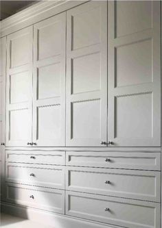 an empty room with white cabinets and drawers