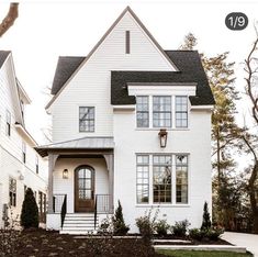 a white house with lots of windows and bushes in front of it on instagram