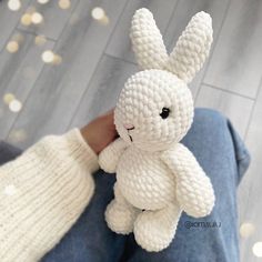 a person holding a white stuffed animal in their hand