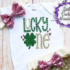 "This is an adorable St. Patrick's Day birthday outfit. This outfit features a bodysuit with the words \"Lucky One\". The outfit is complete with a matching gold headband and shorts. Other bottoms/headbands are available in my shop as well to choose from. HOW TO ORDER: 1.Bodysuit-Select Style and Size from the drop down and add to cart (S/S=Short Sleeve, L/S=Long Sleeve). 2.Add bottom and headband to complete the outfit for best value (optional). 3.Complete purchase and enjoy. All orders are cus Customizable Cute Bodysuit For Birthday, Customizable Cute Birthday Bodysuit, Cute Birthday Bodysuit With Name Print, Cute Bodysuit With Name Print For Birthday, Customizable Cute Onesie For Birthday, Cute Customizable Onesie For Birthday, Day Birthday Outfit, St Patrick's Day Birthday, St Patrick's Day Outfit