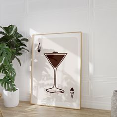 a framed art print with a martini glass on the table next to a potted plant