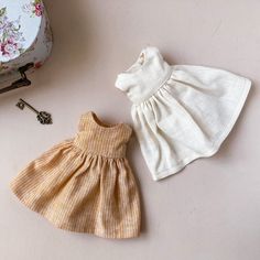 two baby clothes sitting on top of a table next to a suitcase and keychain