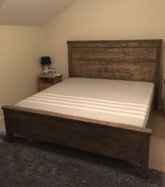 a bed with a wooden headboard and foot board sitting in a room next to a night stand