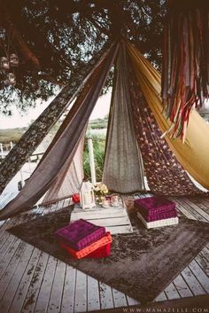 there is a hammock set up on the deck with pillows and rugs