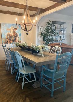 a dining room table with blue chairs and a chandelier hanging from the ceiling