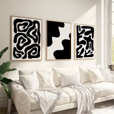 three black and white paintings hang on the wall above a couch in a living room