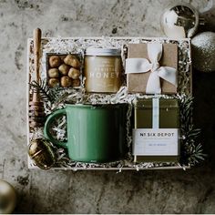 a christmas gift box with coffee, nuts and other holiday treats on a table next to ornaments