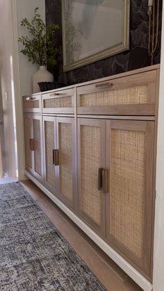 a room with a rug, cabinet and mirror on the wall in front of it