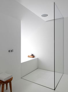 a white bathroom with a glass shower door and stand up shower head in the corner