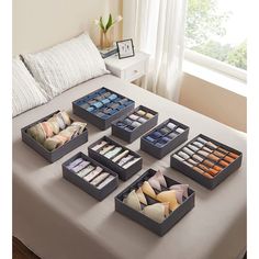 a bed topped with lots of trays filled with different types of pillows and cushions