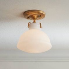 a light fixture with a white glass shade hanging from it's center point on the ceiling