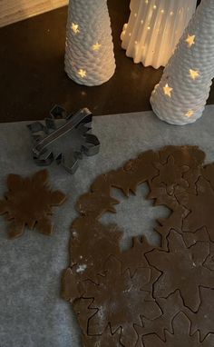 some cookies are laying on the table next to two white vases and one is decorated with snowflakes