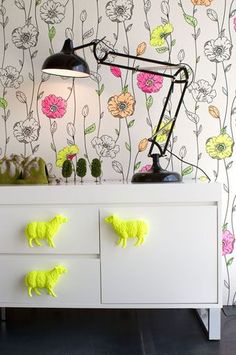 a white dresser topped with drawers covered in neon yellow pom poms and flowers