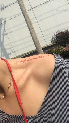 the back of a woman's neck with writing on her left shoulder, and a telephone pole in the background