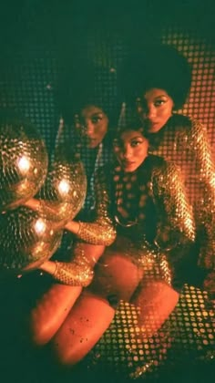 three women in shiny gold outfits posing for the camera with disco balls on their feet