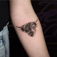 a small black and white cow tattoo on the left arm