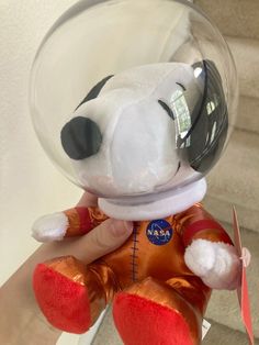 a hand holding a small stuffed animal in a glass bowl on top of a stair case