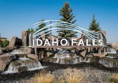 the entrance sign to idaho falls is surrounded by rocks and water cascadings