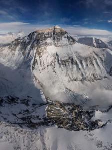 an aerial view of snow covered mountains and clouds