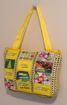 a purse hanging on a wall with yellow trimmings and pictures all over it