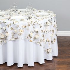 a white table with flowers on it and two wine glasses sitting on top of the table