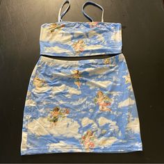 a blue skirt with angels on it sitting on top of a wooden table next to a pair of scissors