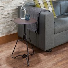 a grey couch sitting next to a table on top of a hard wood floored floor