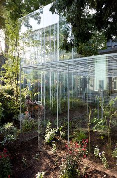 a glass house surrounded by trees and flowers