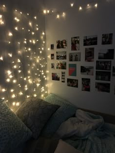 a bedroom with lights strung from the ceiling and pictures on the wall above it,